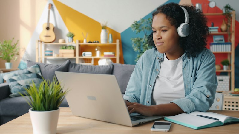 Young woman wearing headphones using laptop at desk